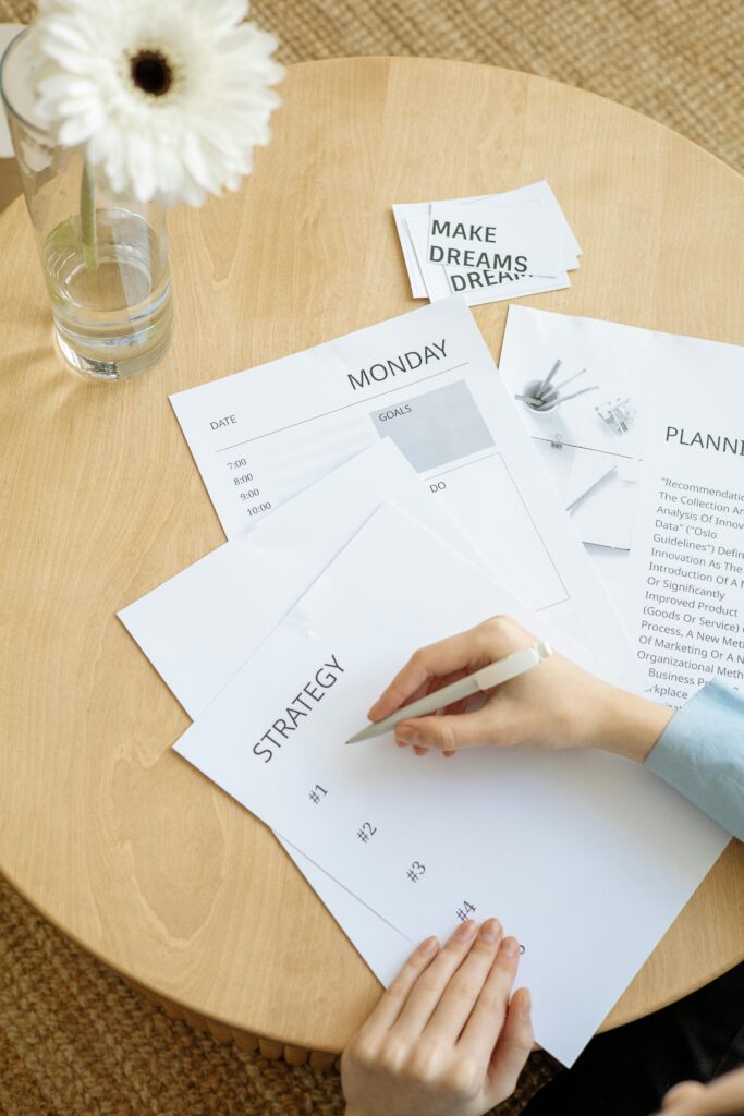 Overhead view of strategy planning papers on a round table with a person writing.